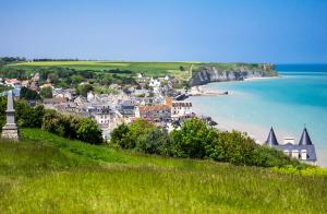 a town on a hill next to the ocean at Il y a de l'amour dans l'air - studio lit king size in Arromanches-les-Bains +7 photos
