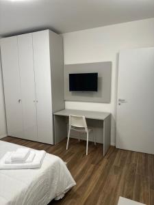 a bedroom with a bed and a desk with a television at San Pellegrino Suites in San Pellegrino Terme