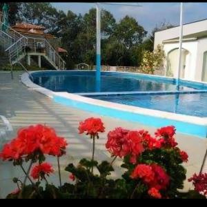a swimming pool with red flowers in front of it at Family Hotel Kentavar 2 in Byala