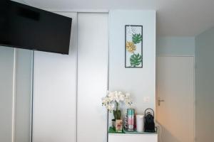 ein Wohnzimmer mit einem TV und einer Vase aus Blumen in der Unterkunft The Anatole - Cosy & calm apartment in Villeurbanne