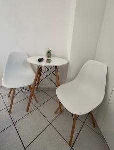 two white chairs and a table with a plant on it at Valente Rooms Kythira in Kythira