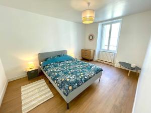 a bedroom with a bed with a blue comforter at Appartement centre-bourg de Bessines in Bessines-sur-Gartempe