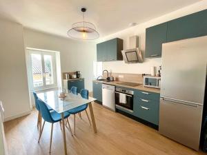 a kitchen with a table and chairs and a refrigerator at Le Giraudoux - Centre bourg Bessines in Bessines-sur-Gartempe