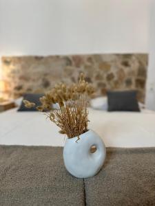 a white vase with flowers sitting on a bed at Valente Rooms Kythira in Kythira