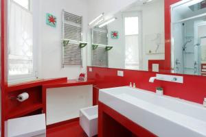 a red bathroom with a white sink and a mirror at Karol Apartment Rome in Rome