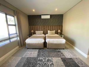 a bedroom with two beds and a large window at Khaya Elihle Guest House in Hazyview