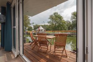 een veranda met een tafel en stoelen en uitzicht op het water bij Hafenresort Karnin _ Hausboot Pit in Karnin