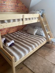 drewniane łóżko piętrowe w pokoju z ceglaną ścianą w obiekcie Bokun Dunava w mieście Erdut