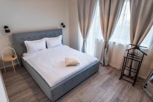 a bedroom with a bed with a blue headboard and two windows at TEILOR Apartments 1 in Floreşti