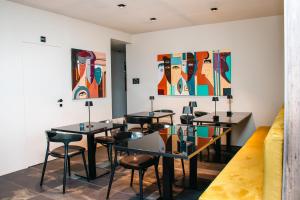 ein Zimmer mit Tischen, Stühlen und Gemälden an der Wand in der Unterkunft Etrus - Boutique Room & Rooftop in Pontecagnano