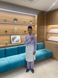 a man standing in front of a blue couch at The Signature Serviced Suites Puchong in Puchong