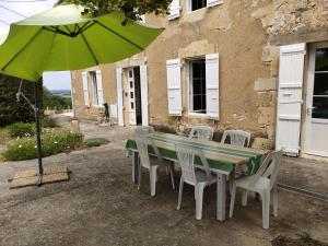 una mesa con sillas y una sombrilla verde en Au bon vivre, en Saint-Orens-Pouy-Petit