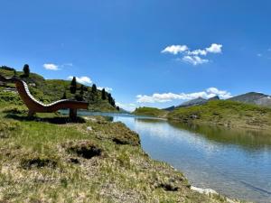 ławkę siedzącą na brzegu wody w obiekcie Obertauern Fewo Alps -Top 11 by Kamper w mieście Obertauern