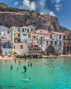 een groep mensen in het water op een strand bij Kalura Sea House in Cefalù