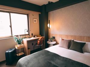 1 dormitorio con cama, escritorio y ventana en R Hotel-The Atelier Shinsaibashi East, en Osaka