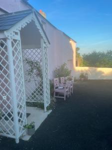 cenador blanco con sillas y mesa en The Pink Cottage (upstairs suite) & Secret Garden, en Whitehead