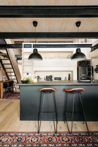 a kitchen with a black counter and two stools at HOUSEBOAT FRED Prague in Prague