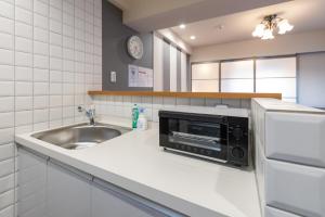 a kitchen with a sink and a microwave at H2H Dotonbori in Osaka