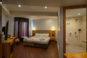 a bedroom with a bed and a bathroom with a shower at Emerald Hotel in Āīzawl