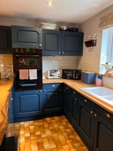 a kitchen with navy blue cabinets and a sink at New Forest Spacious Family House in New Milton