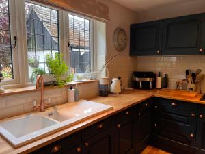 a kitchen with a sink and two windows at New Forest Spacious Family House in New Milton