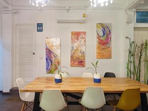 een houten tafel en stoelen in een kamer met schilderijen bij The Ellis Bangkok in Makkasan