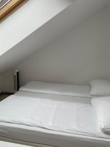 uma cama branca com lençóis e almofadas brancos em KHAN Apartments LJUBLJANA em Ljubljana