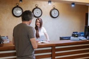 a man and a woman standing at a counter with clocks on the wall at Guest House Valevtsi in Valevtsi +198 photos
