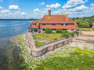 an old house on the shore of a body of water at Pass the Keys Historic Waterfront Home in Bosham in Bosham