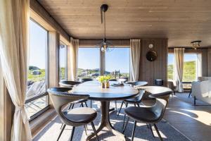 a dining room with a table and chairs and windows at The Magic View of Lofoten - Nature & SEA in Sørvågen