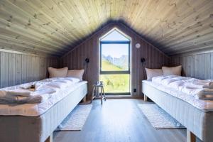 two beds in a room with a window at The Magic View of Lofoten - Nature & Sea in Sørvågen
