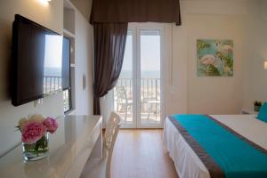 a hotel room with a bed and a television and a balcony at Hotel Mon Cheri in Riccione