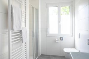 a white bathroom with a toilet and a window at JUFA Hotel Garni Stubenberg am See in Stubenberg
