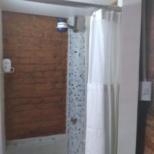 a shower with a white shower curtain and a brick wall at Studio SUITE M&J in Caracas