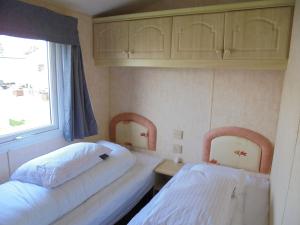 two beds in a small room with a window at Waterside: Waterside Salisbury:- 6 Berth Large Wrap Around Veranda in Ingoldmells