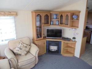 a living room with a desk with a tv and a chair at Waterside: Waterside Salisbury:- 6 Berth Large Wrap Around Veranda in Ingoldmells