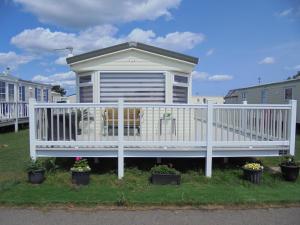 a house with a white deck with a cow on it at Waterside: Waterside Salisbury:- 6 Berth Large Wrap Around Veranda in Ingoldmells