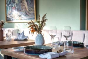 una mesa de madera con platos y vasos y un jarrón. en Feinheit Hotel & Restaurant, en Halsenbach