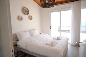 a white bedroom with a large bed and a large window at Meneou Houses by the Sea in Larnaca