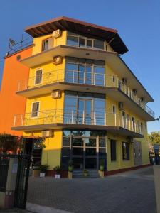 a yellow building with balconies on the side of it at Hotel PRINC in Velipojë