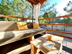 eine Holzbank auf einer Terrasse mit einem Tisch in der Unterkunft Mobilehome Adams Glamping - Camp Adriatic in Primošten