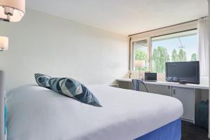 une chambre d'hôtel avec un lit et une télévision dans l'établissement Kyriad Direct Le Bourget Gonesse, à Gonesse