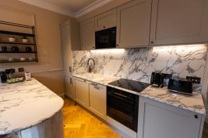 una cocina con armarios blancos y encimeras de mármol en Boutique Apartment in Camden road, en Londres