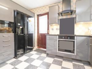 a kitchen with stainless steel appliances and a checkered floor at 23 Wolsey Close in Thornton