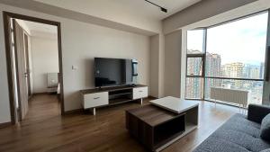 - un salon avec une télévision et une grande fenêtre dans l'établissement Mayseven serviced apartment, à Oulan-Bator