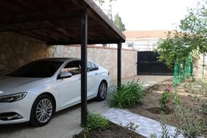 een witte auto geparkeerd onder een hoes op een oprit bij Gallipoli Dublex House in Canakkale