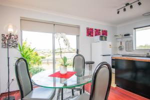 a dining room with a glass table and chairs at Gairdner Cottage - something a bit different! in Albany