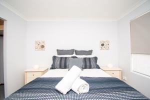 Un dormitorio con una cama azul y blanca con toallas. en Gairdner Cottage - something a bit different! en Albany
