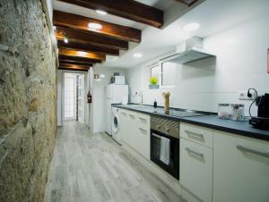 eine große Küche mit weißen Geräten und einer Steinmauer in der Unterkunft Casa das Vigas I in São Mamede de Infesta