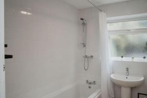 a white bathroom with a sink and a tub and a toilet at Valley Park House - By Sigma Stays in Crewe